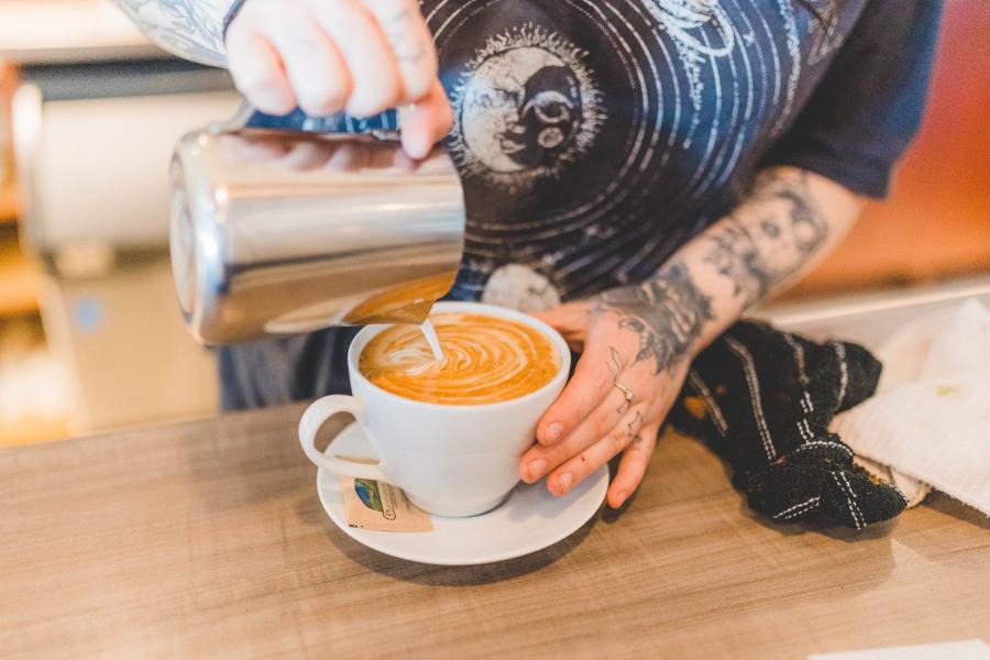 Pouring steamed milk in a coffee at Café Europa