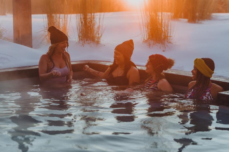 four girls sitting in an outdoor hot tub in winter