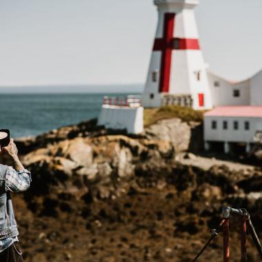 a man taking a picture of the head harbour lighthouse in campobello