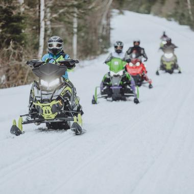 people snowmobiling on a trail in new brunswick