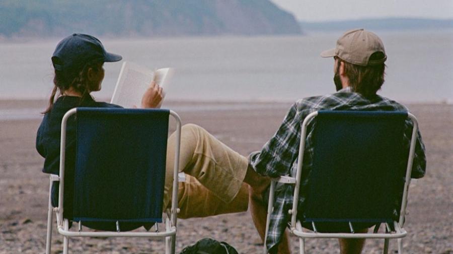 two people sitting in front of a lake