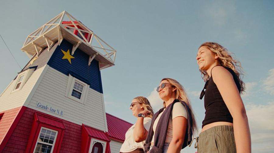 three people in front of a lighthouse