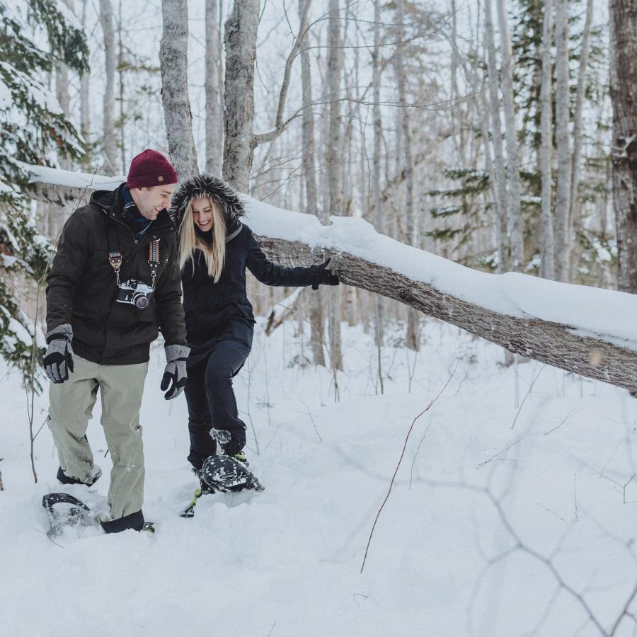 Man and woman snowshoeing through a snowy forest