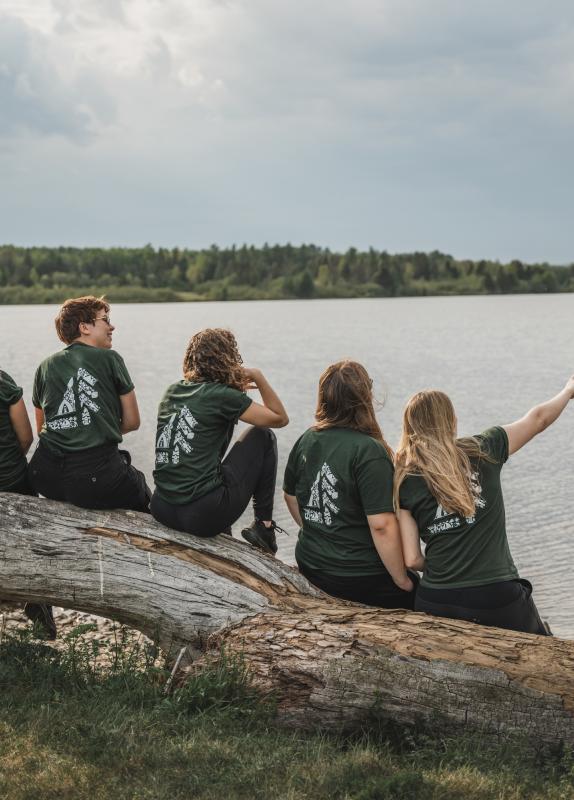 Six people sitting on a rock overlooking a lake.