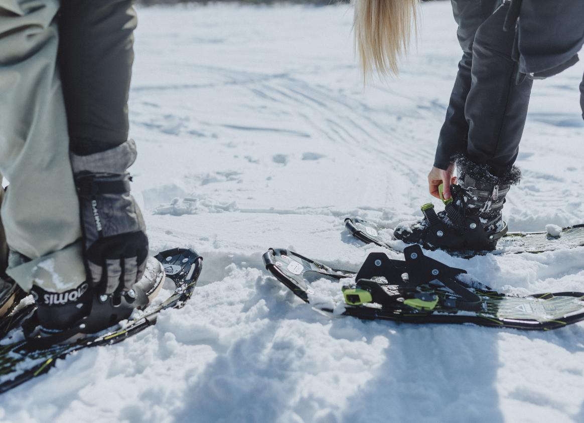 Close up of snowshoes being put on boots in the snow