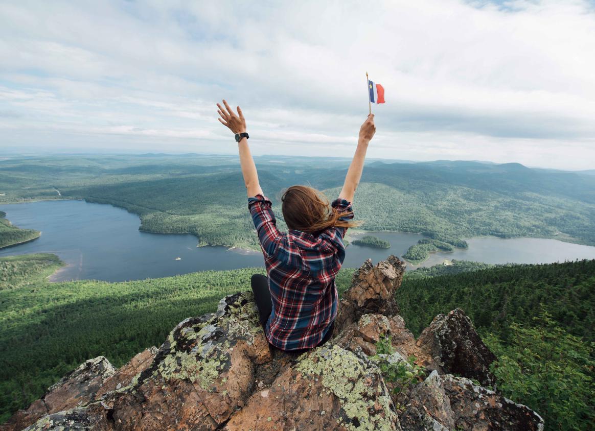 A person sitting on a rock looking out at a gorgeous view of the landscape.