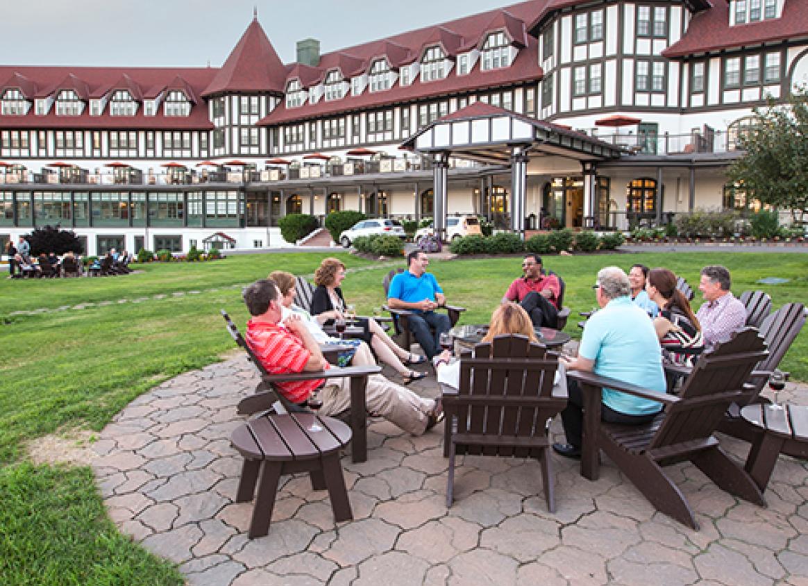 A group of people sitting on Adirondack chairs outside of an inn in Saint Andrews, New Brunswick